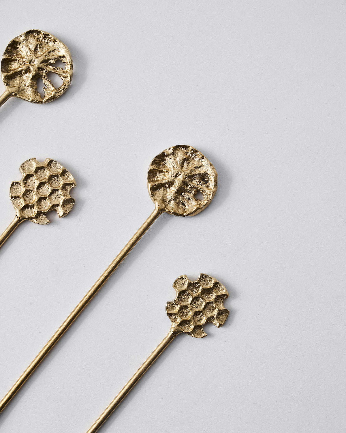 Close-up of gold Dawa stirrer tops with honeycomb and pod textures.