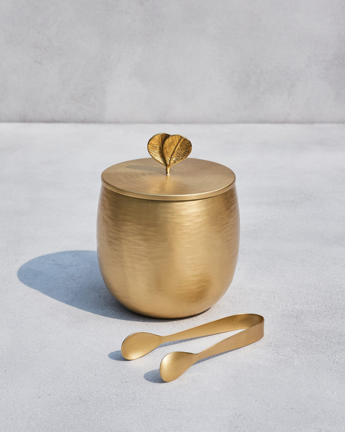 Gold Champa ice bucket with a leaf lid knob and matching tongs.