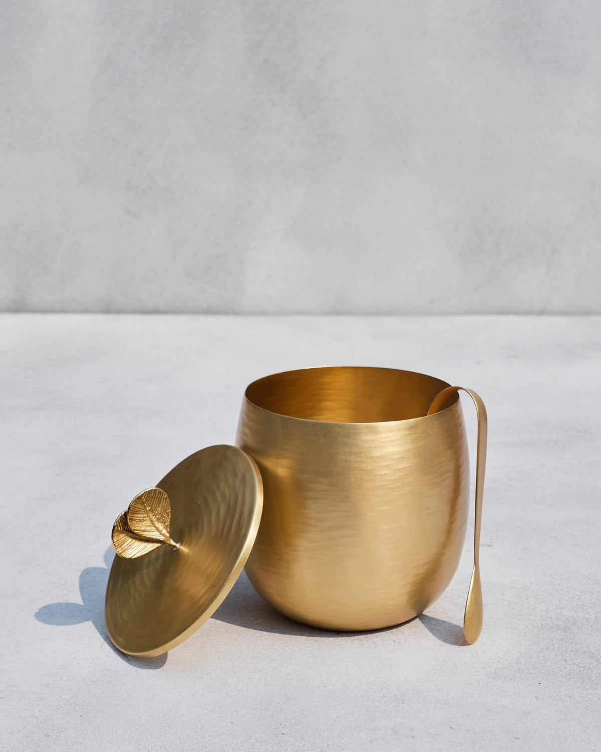 Open gold Champa ice bucket with its leaf lid and a long serving spoon.