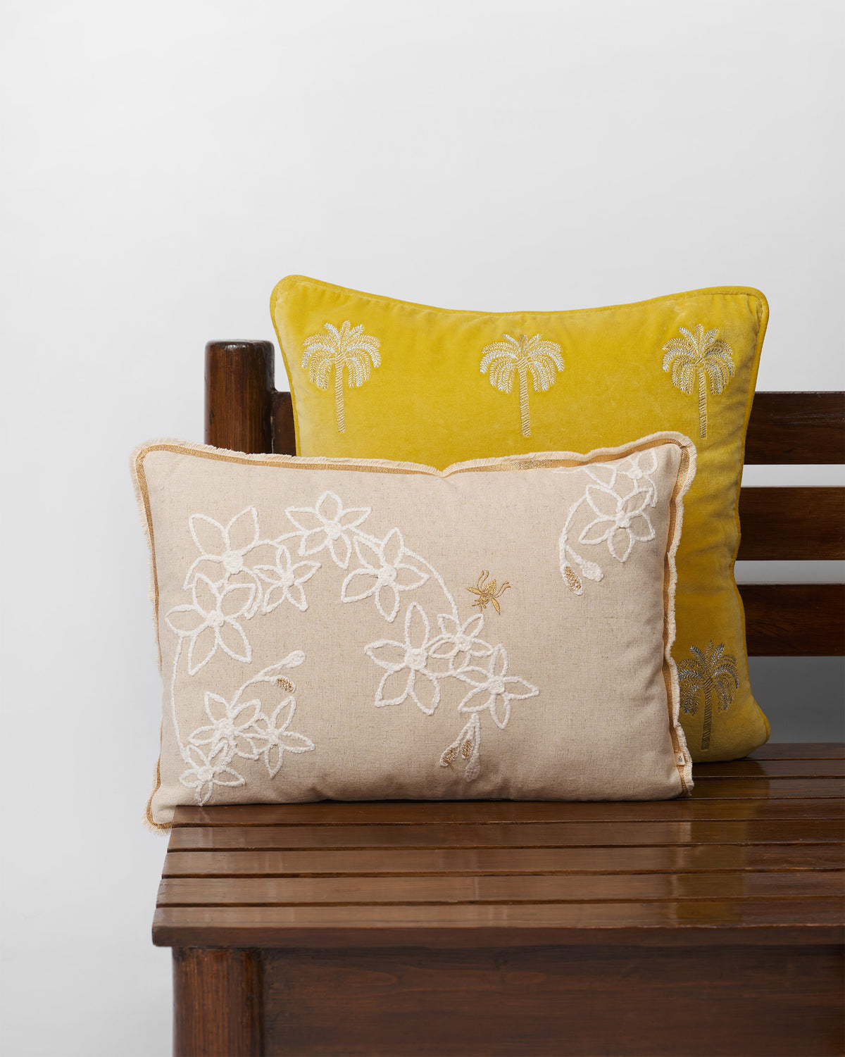 Madhu cushion cover with white embroidered flowers and a bee.