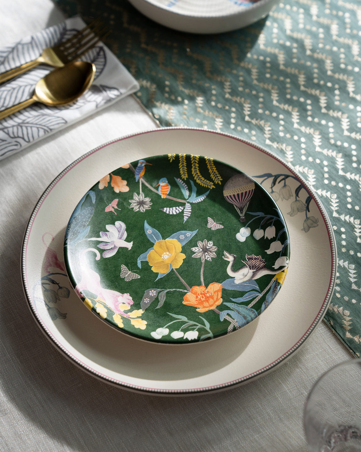 Emerald Myra quarter plate with botanical wildlife print stacked on a cream dinner plate.