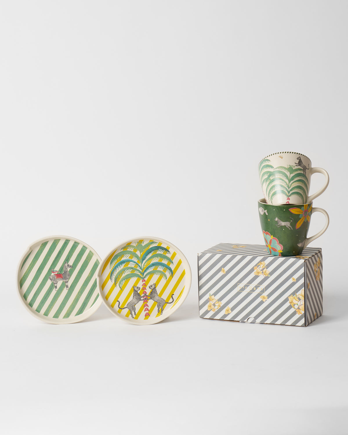 Teatime set mugs stacked beside a striped gift box.