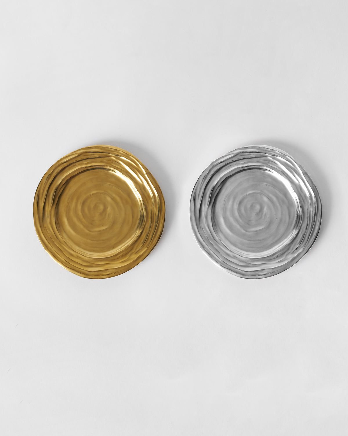 Pair of Dhaara Quarter Plates in gold and silver, seen from above.