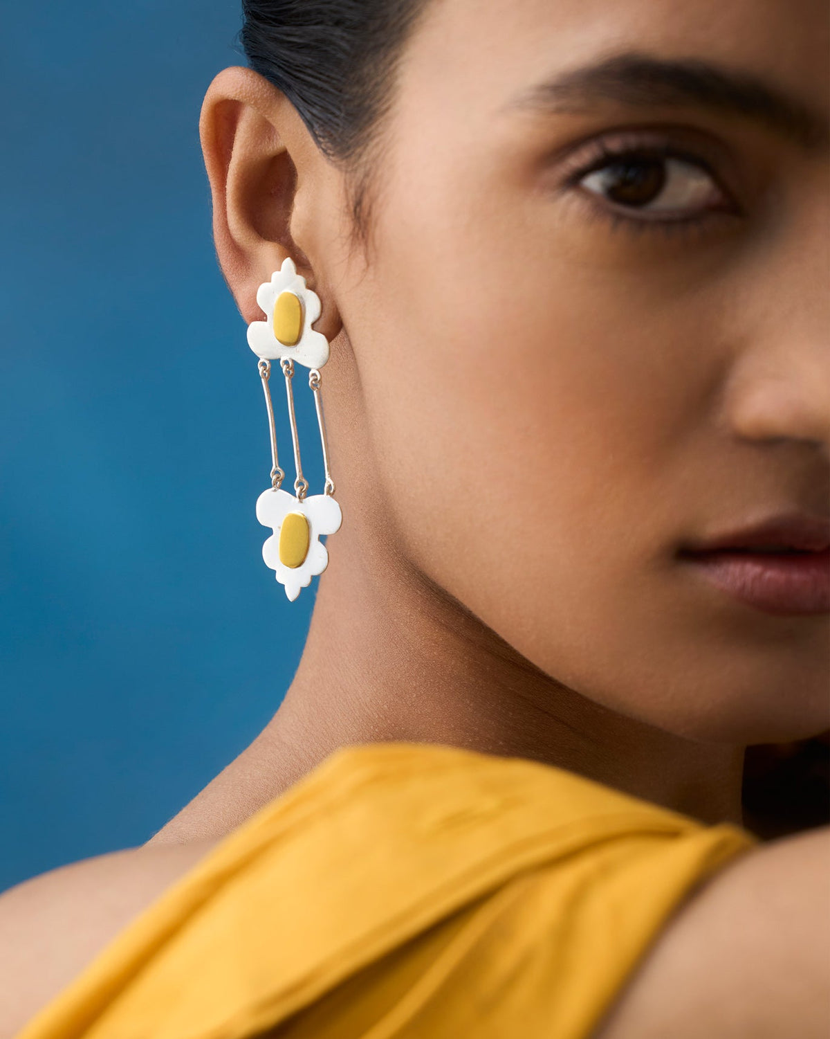Side view of Champa Drop Earrings with white petals worn by a person.