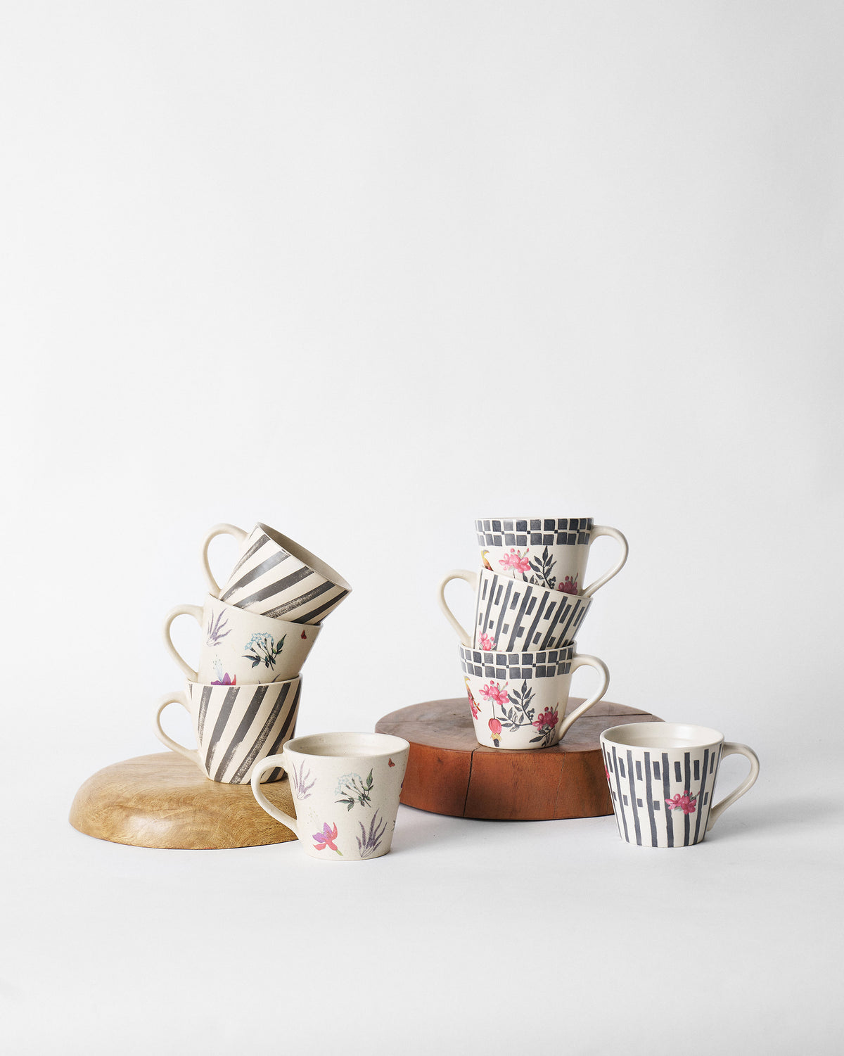 Tropic Espresso Mug Set arranged on wooden stands, with striped and floral designs.