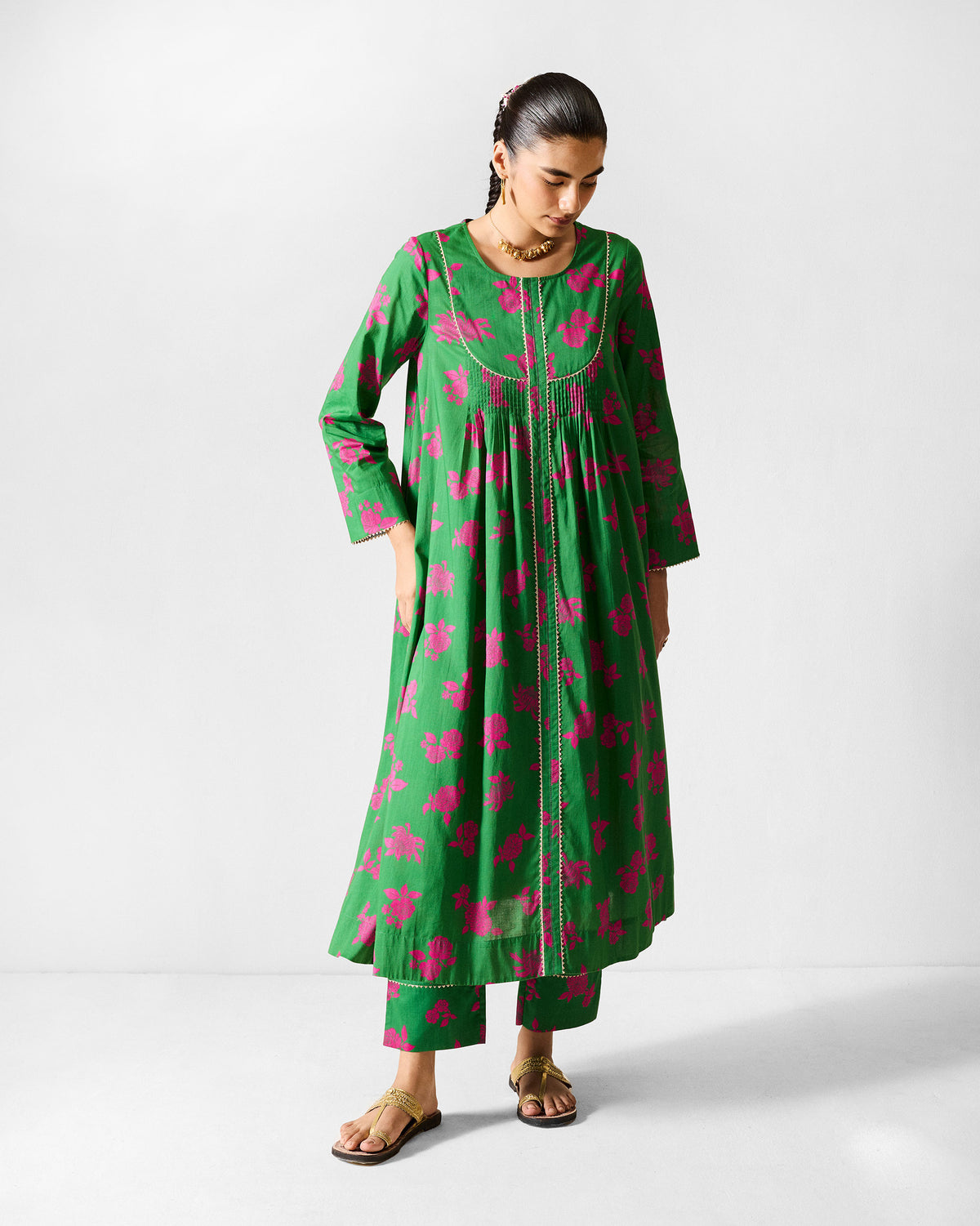 Person wearing a green Ayat kurta set with pink florals and gold yoke piping.