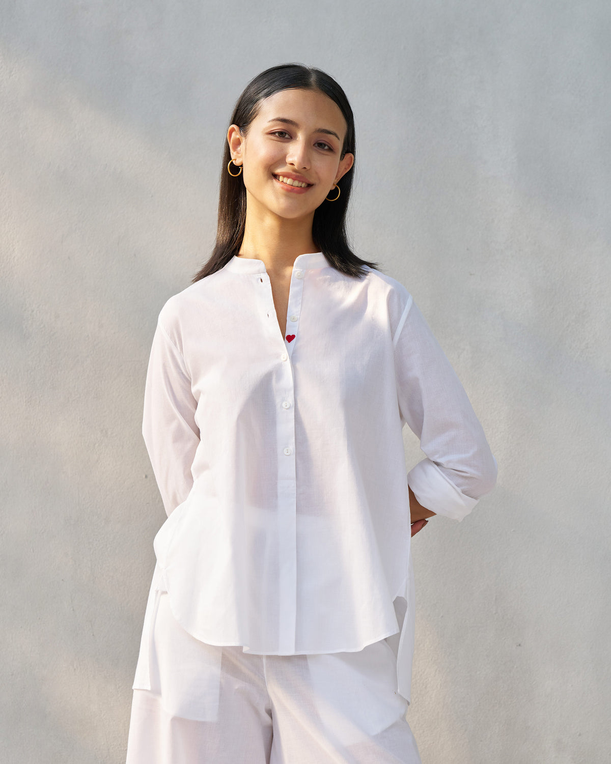 White mandarin collar top set showing a red heart on the open placket.