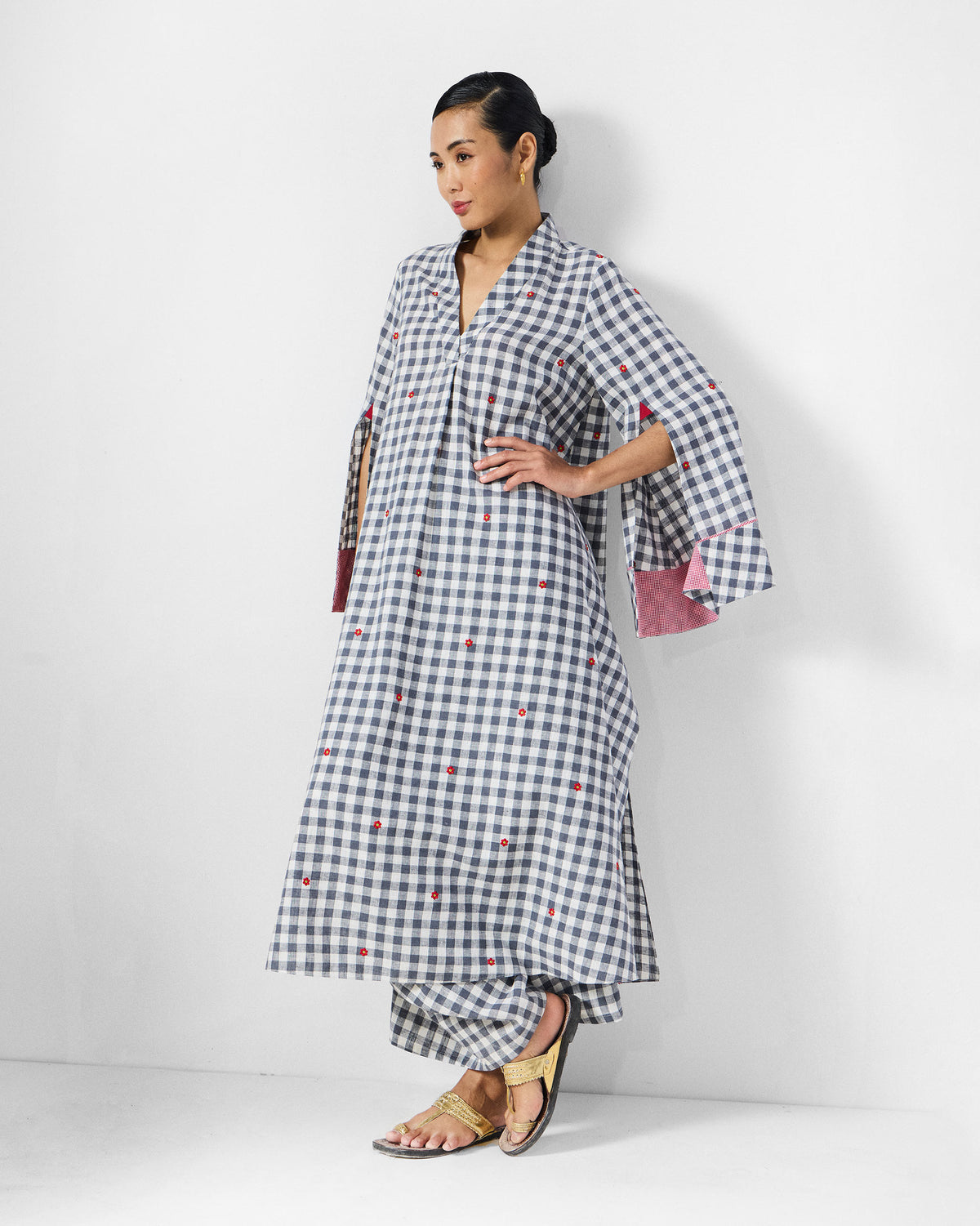 Person wearing a grey and white check kurta set with red floral embroidery.