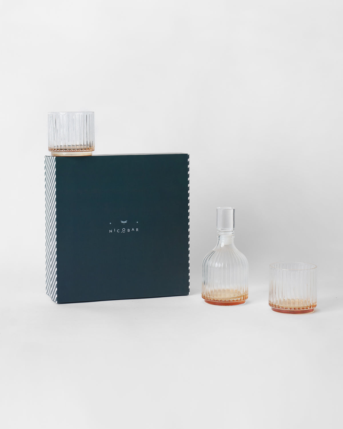Tarang Bar Gift Set decanter and ribbed glasses beside its navy box.