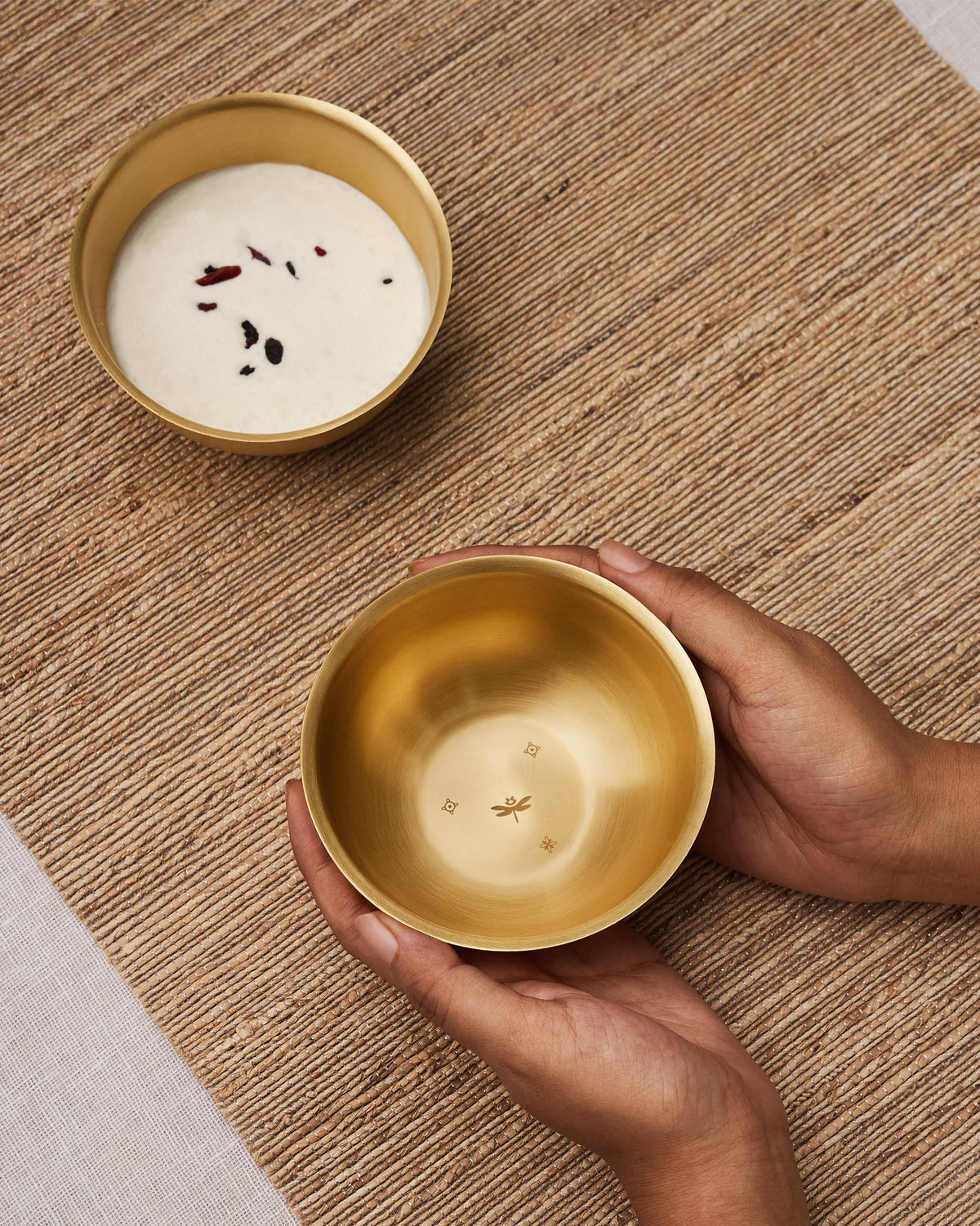 Madhu brass dessert bowl with dragonfly etching held in hands.