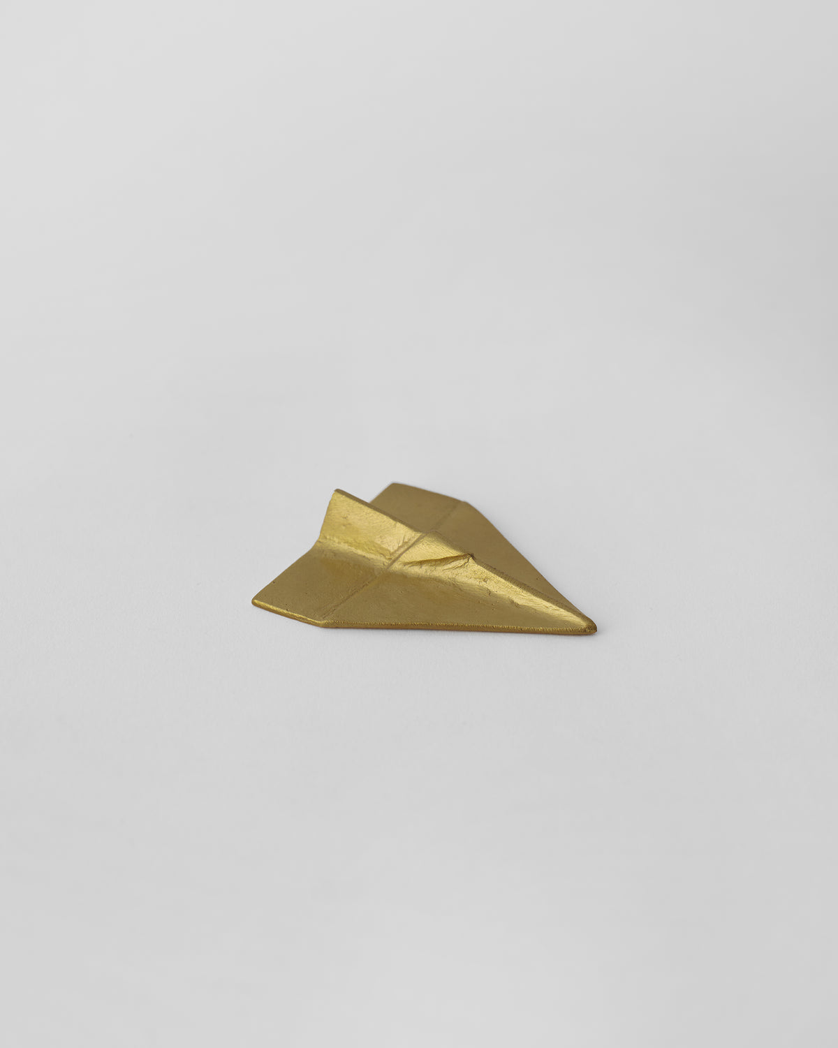 Flight Origami in gold, shaped like a folded paper plane.