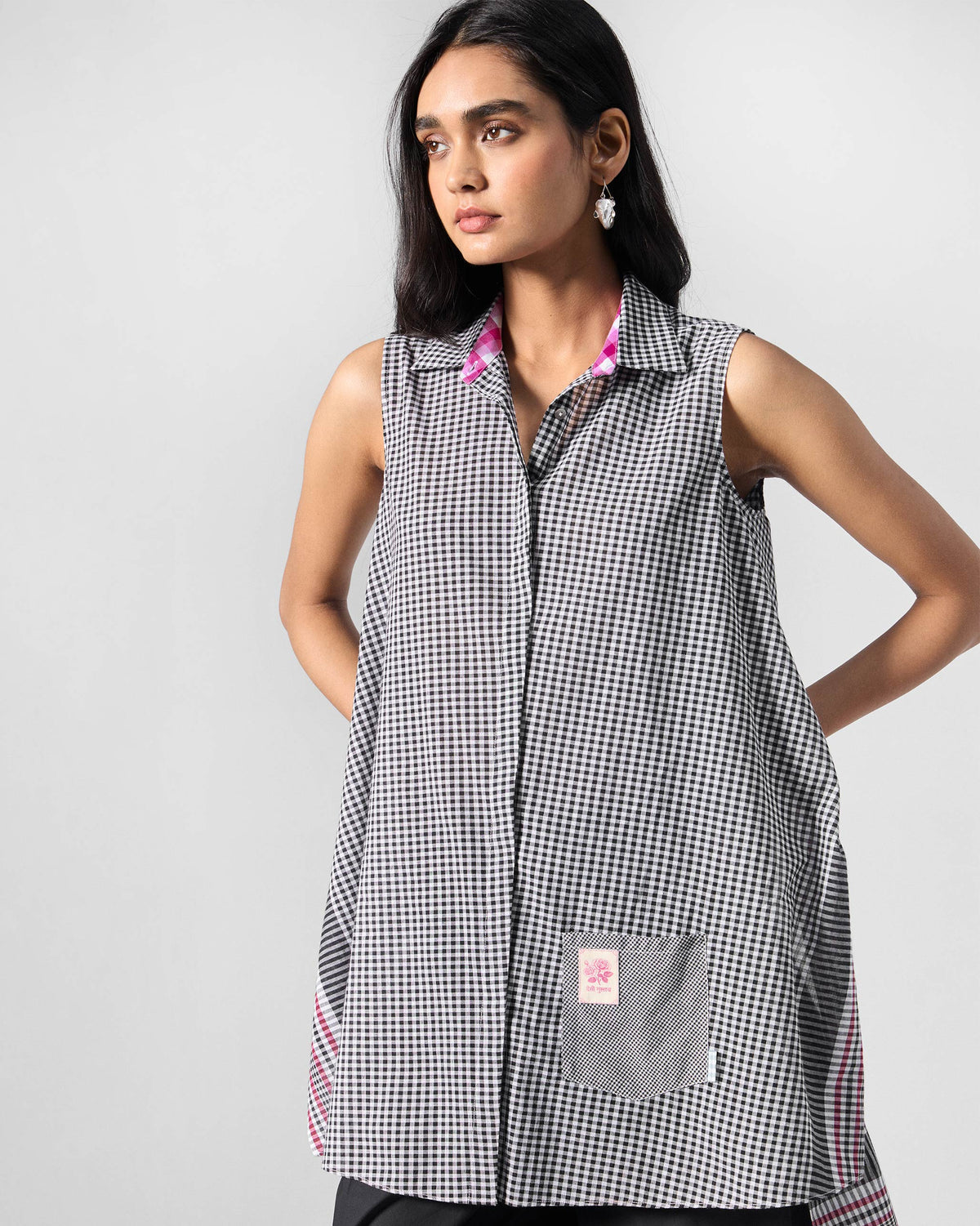 Person wearing a black and white check sleeveless tunic.