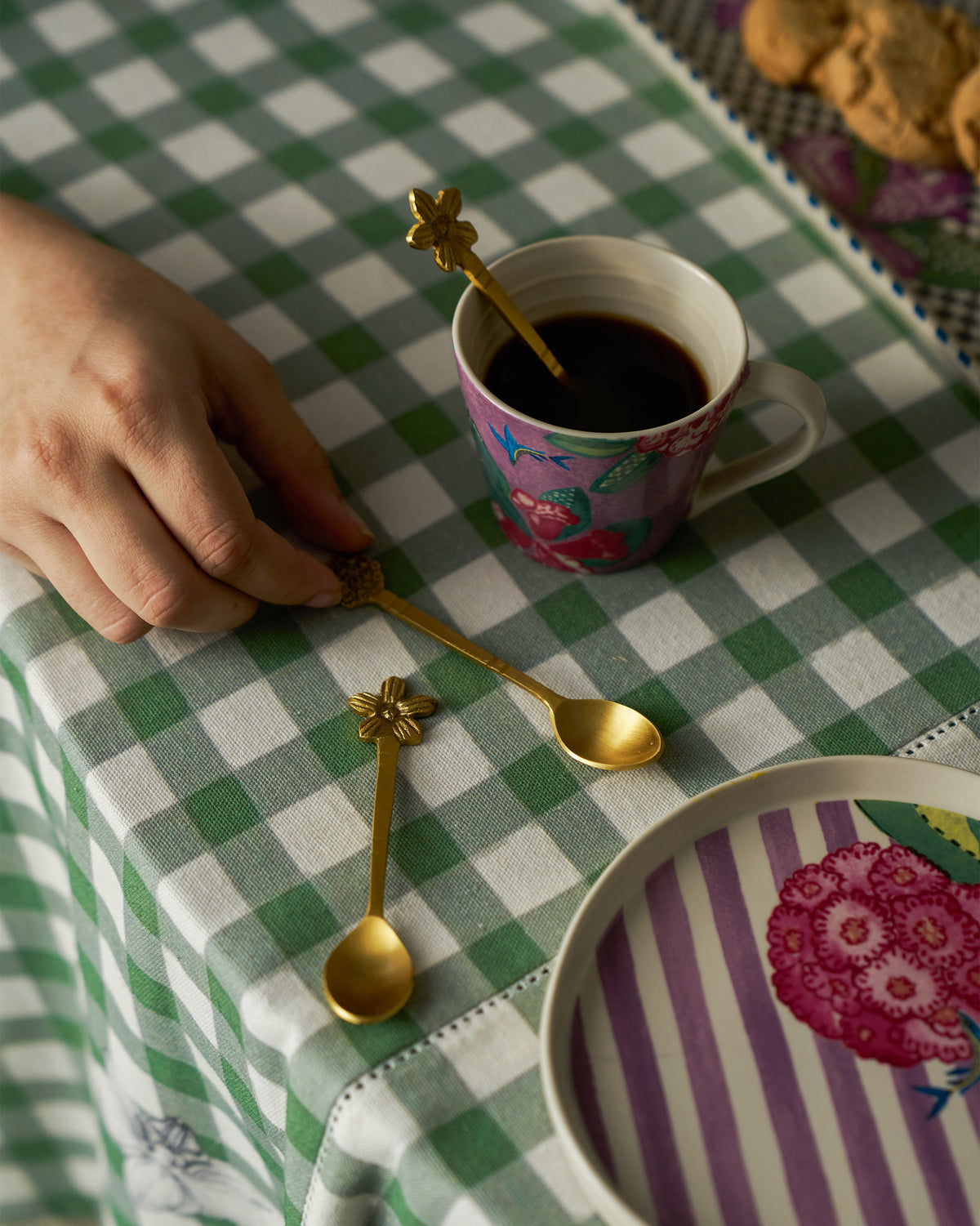 Gold Bloom Coffee Spoons on a table with a floral mug of coffee.