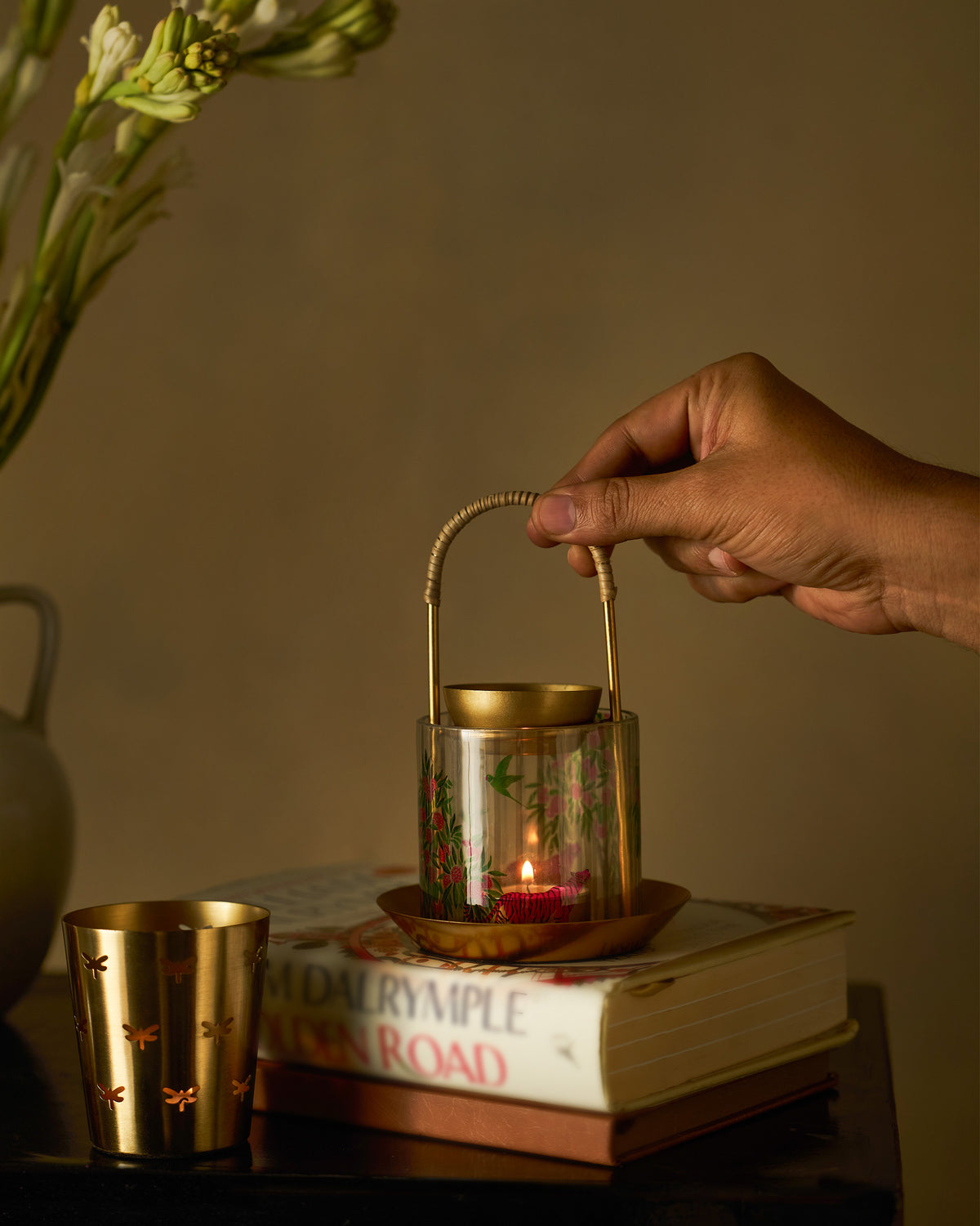 Hand lifting a lit Kandy diffuser with pink blossom glass sleeve.