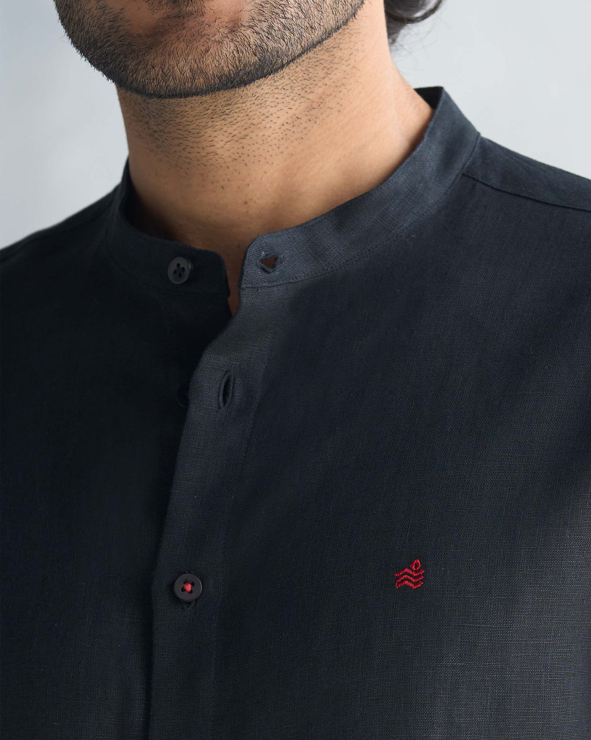 Close-up of a black Nawab Shirt showing the band collar and red chest embroidery.