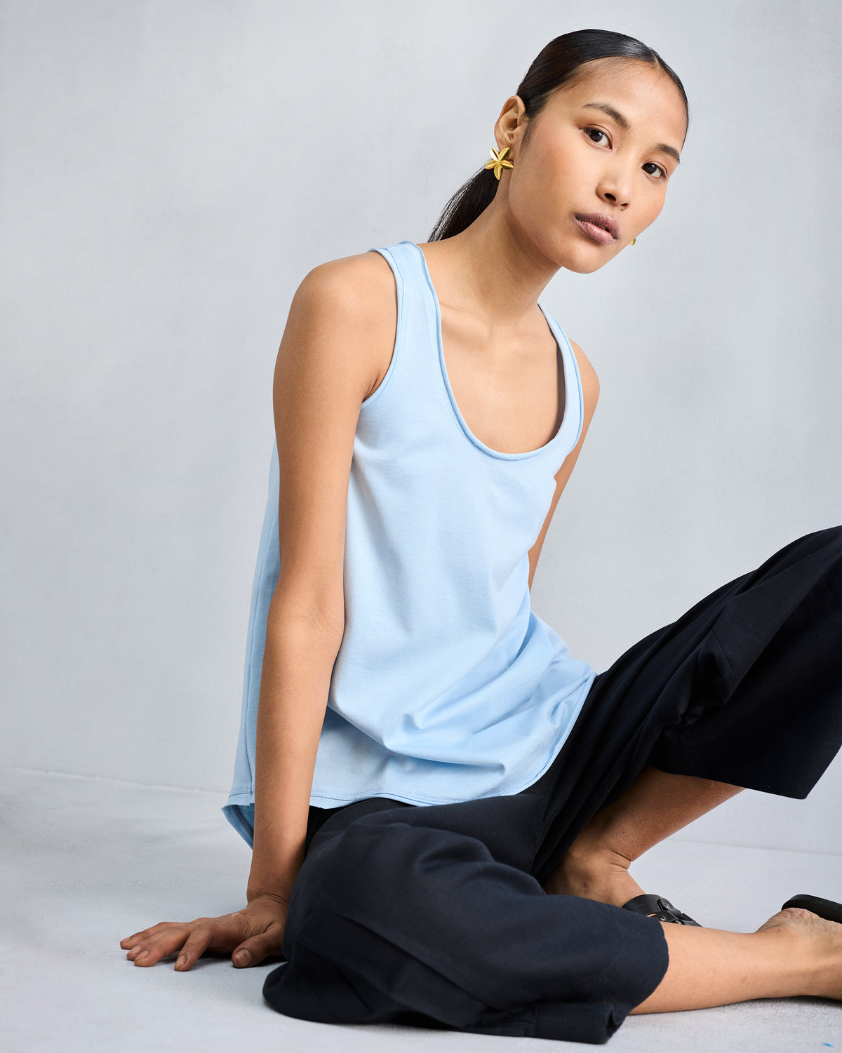 Person wearing a light blue racerback tank with a scoop neckline.
