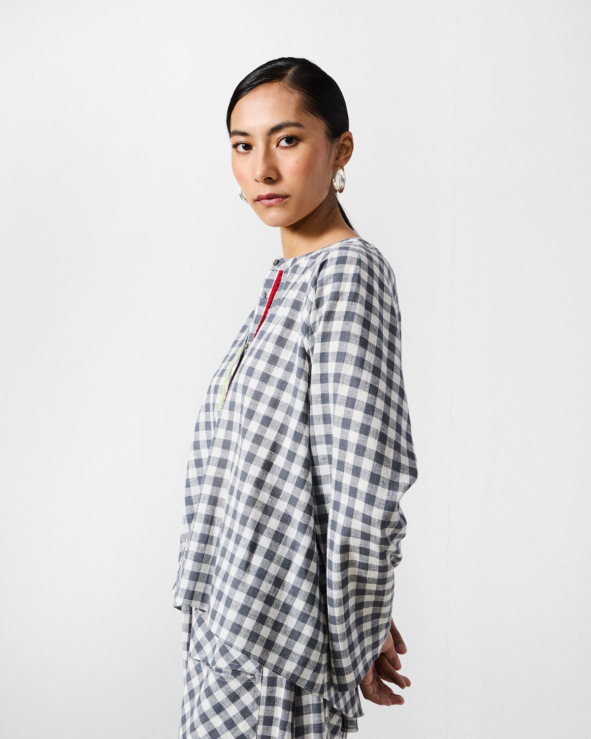 Side view of a charcoal and white check Zil top with flared sleeves.