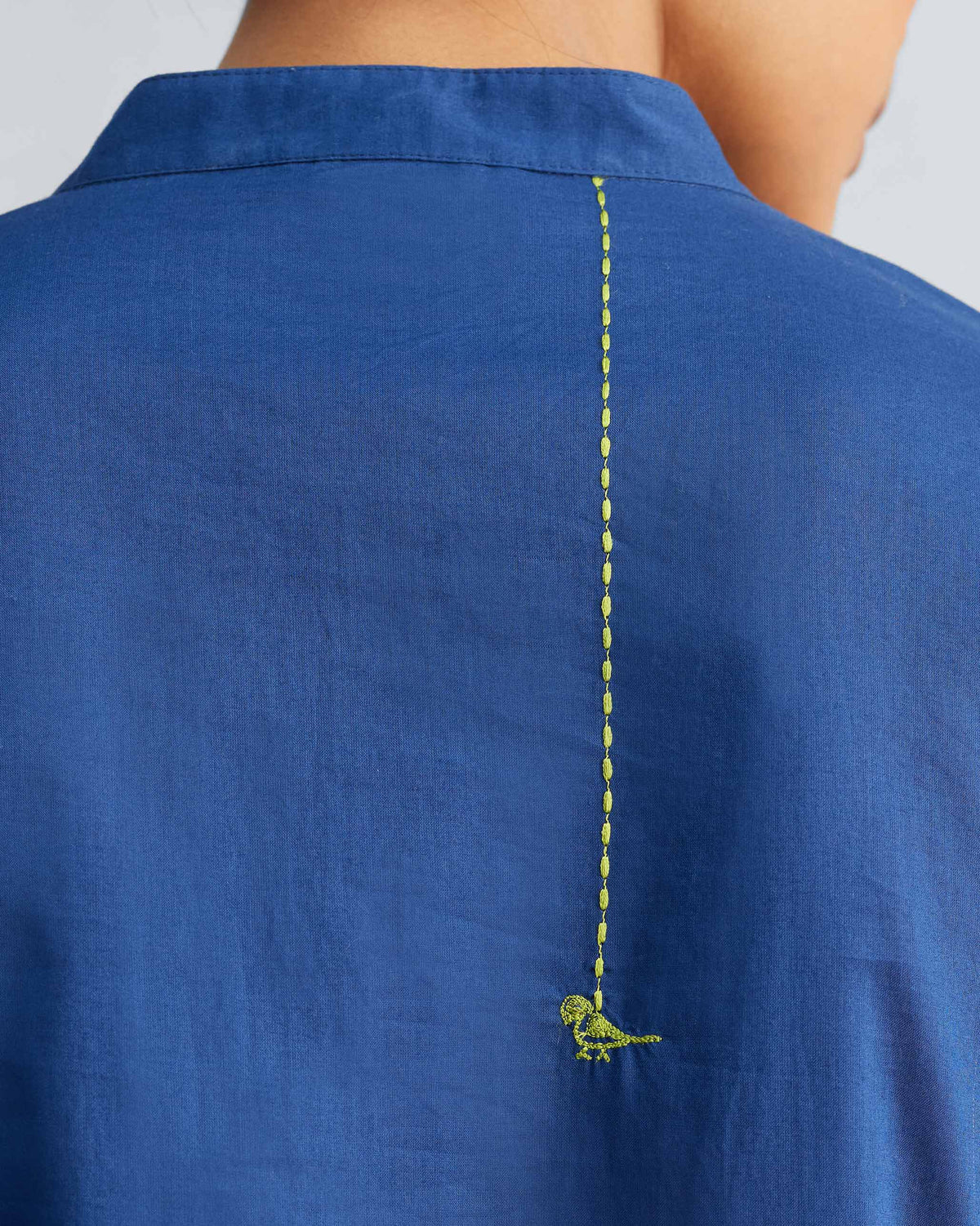 Close-up of a lime green bird embroidery on the back of a navy kurta.