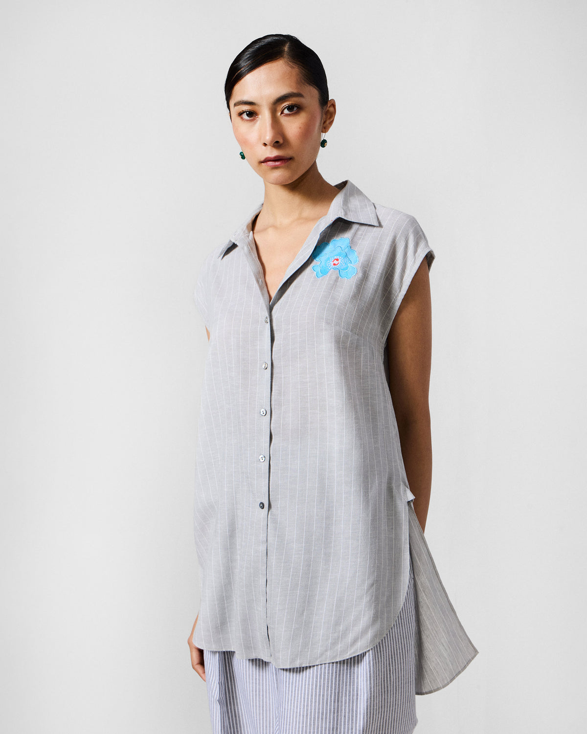 Person wearing a grey striped Rin top with blue floral chest embroidery.