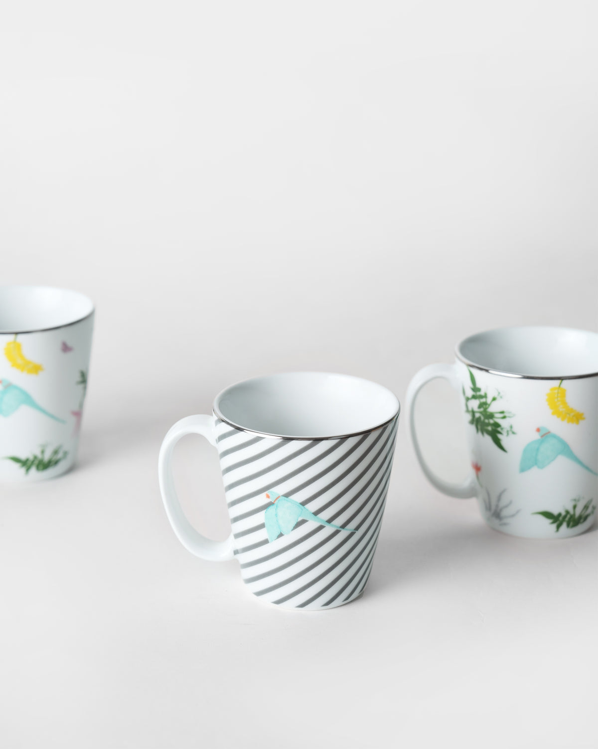 Botanical Coffee Mugs mixing grey stripes with a blue bird and tropical foliage.