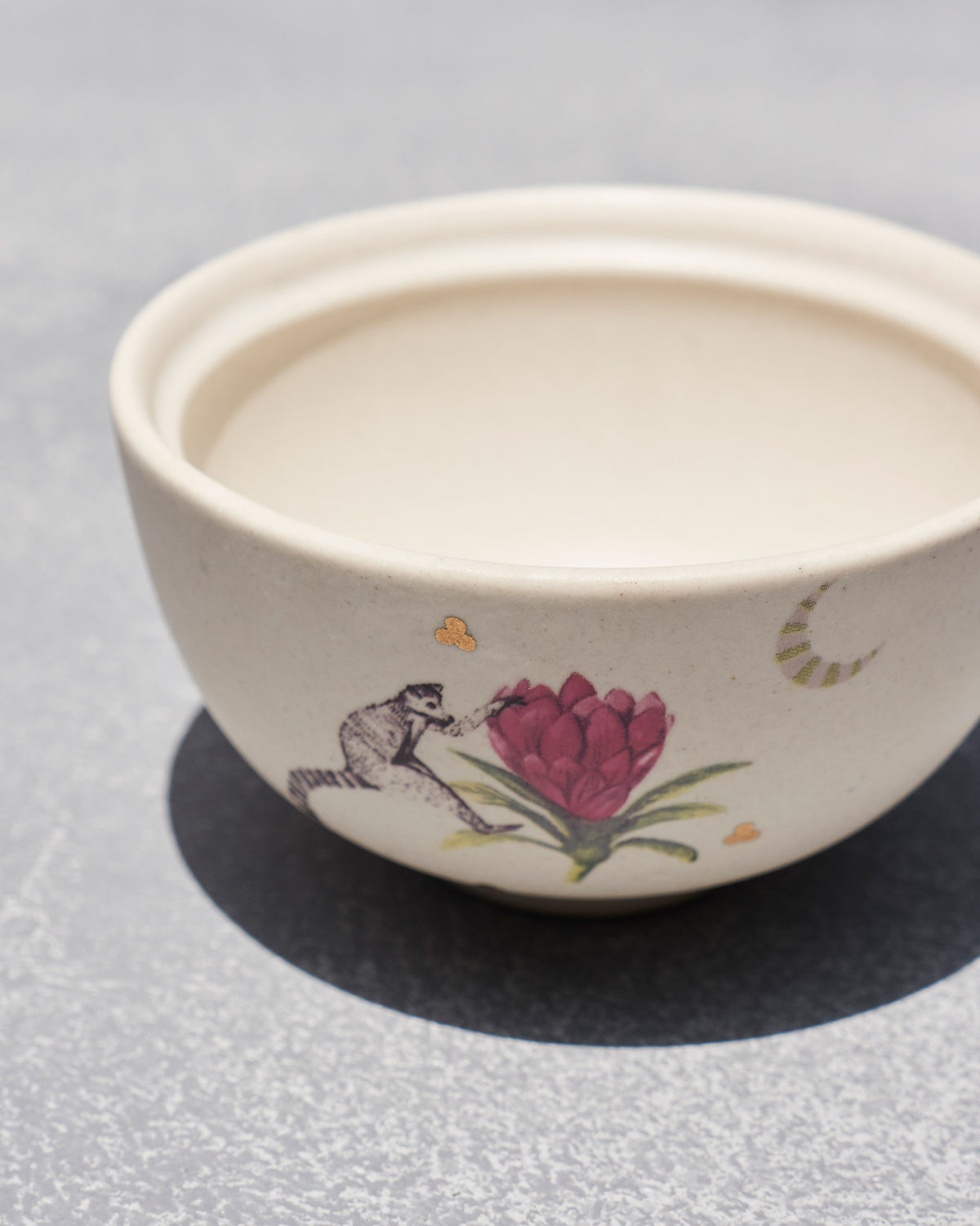 Overhead view of a cream Lemur katori with flower and lemur motif.