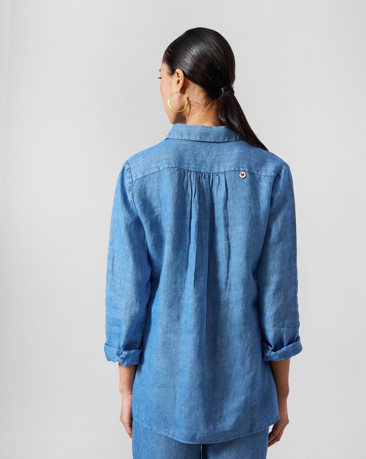 Back of a blue Mati shirt with a small red heart on the yoke.