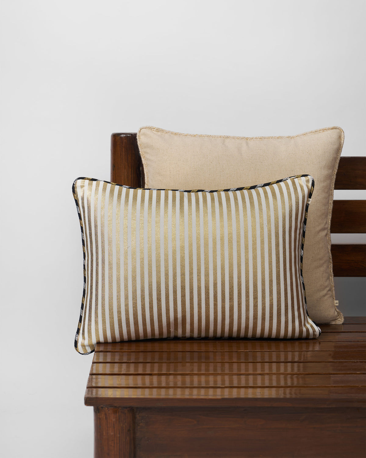 Midas cushion cover with gold and cream stripes and a piped edge.