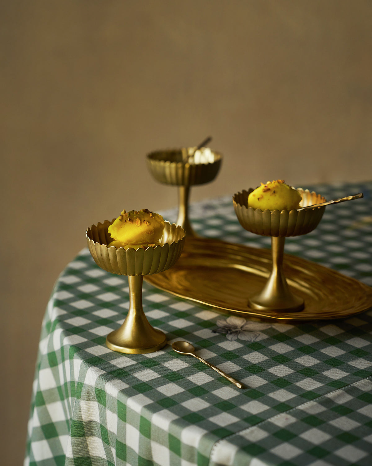 Gold Dhaara Gelato Cups filled with dessert on a table with spoons.