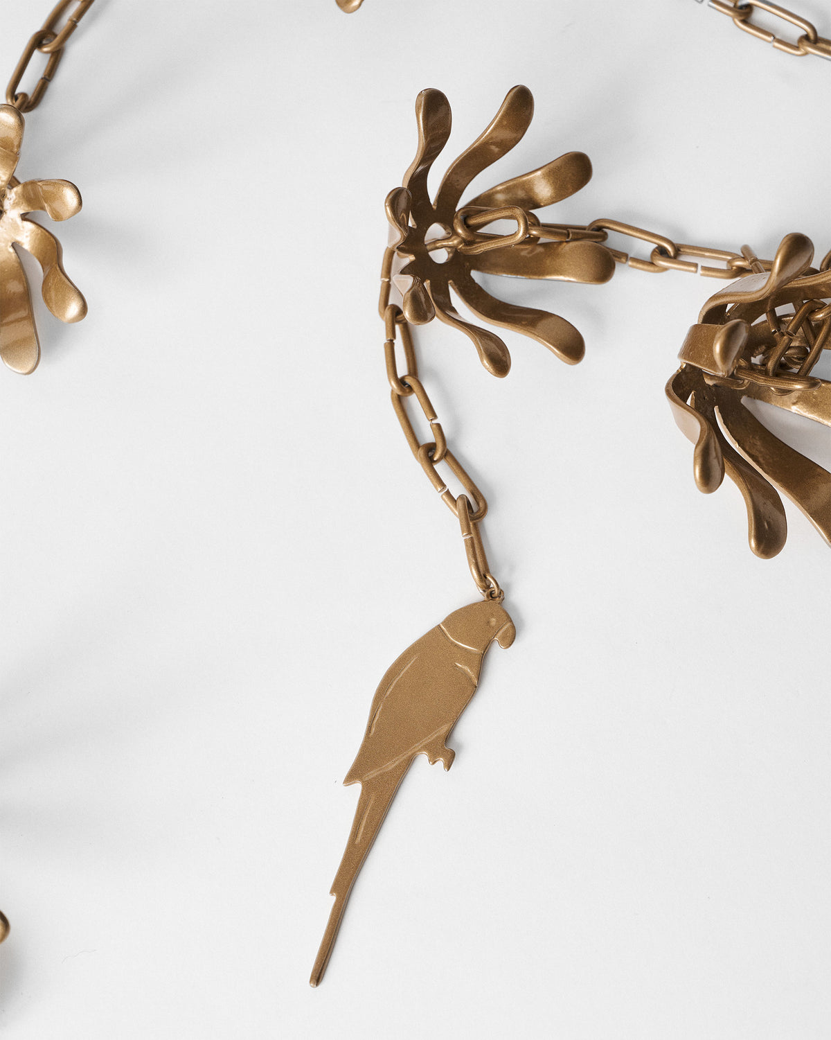 Close-up of the Madagascar Rain Chain showing a parrot pendant and petal-shaped links.