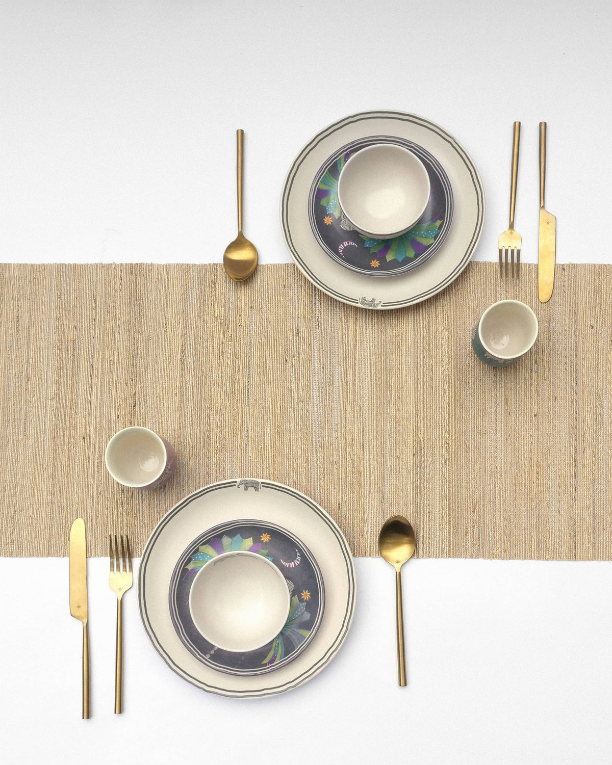 Table set for two with the Tusk Dinner Set for 2 and gold cutlery.
