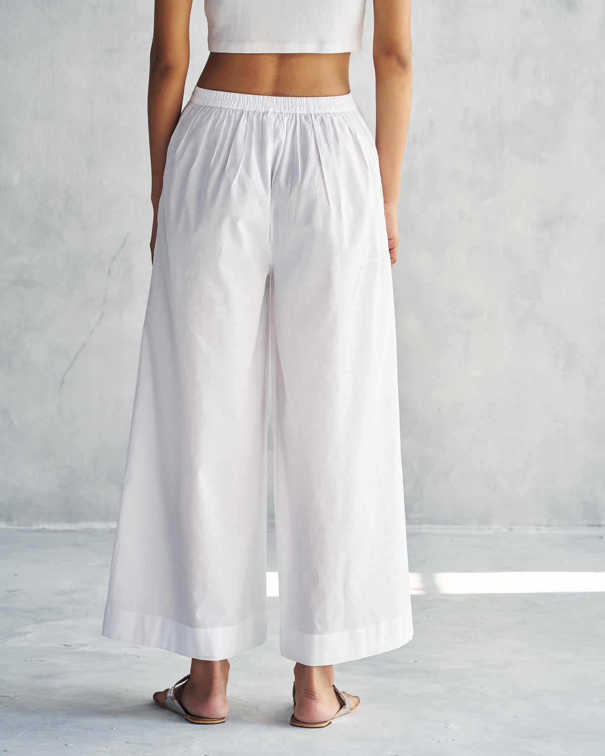 Back of white wide trousers from the Alba set worn by a person.
