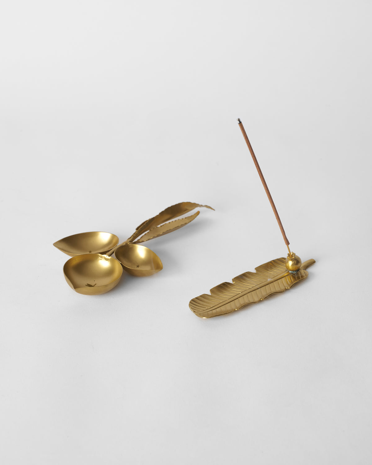 Taal brass leaf incense holder and three-cup diya laid flat.