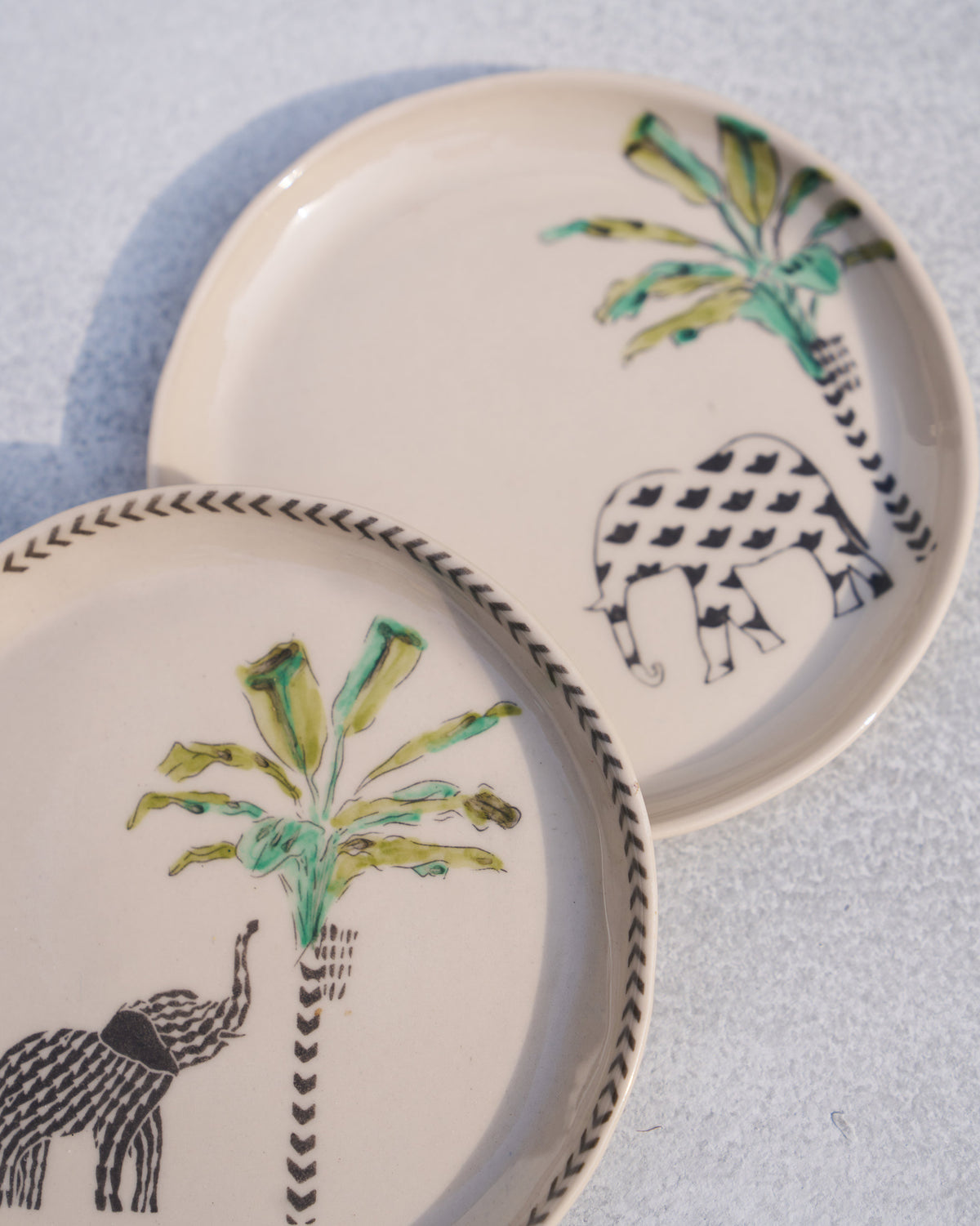 Close-up of coastal tea plates with patterned elephants and green palm trees.