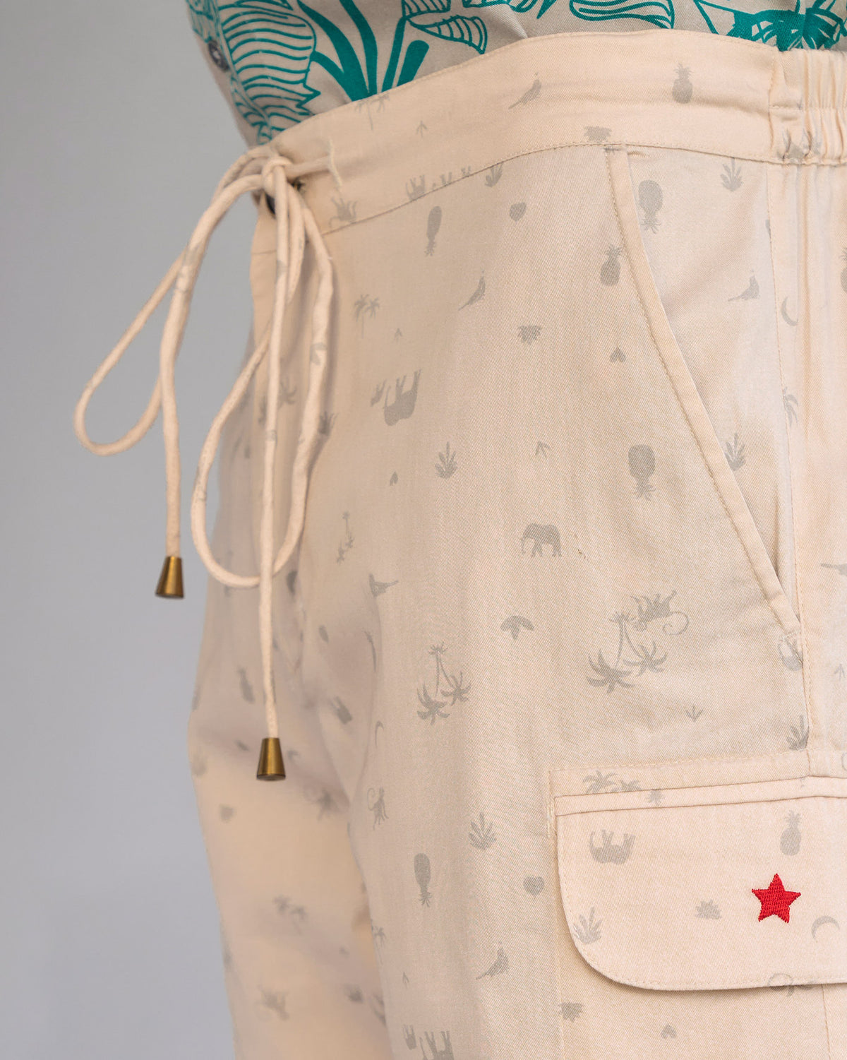 Close-up of beige Luna Shorts showing the drawstring waist and a cargo pocket with a red star.