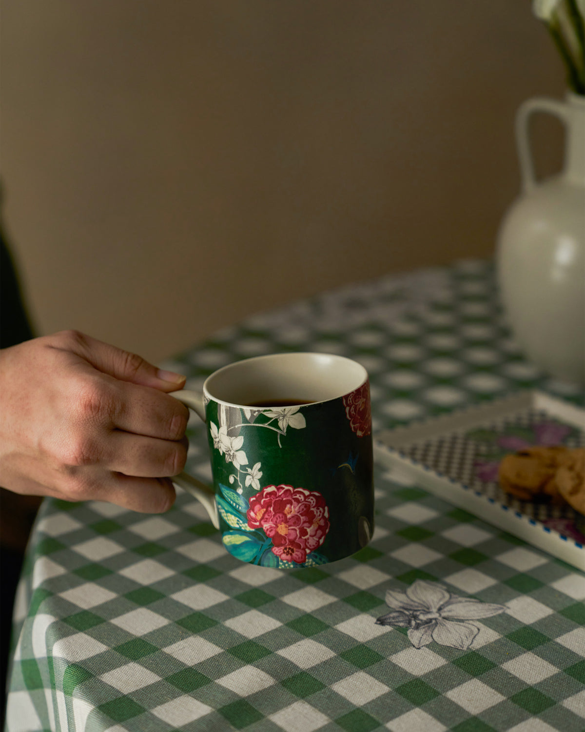 Hand holding a green buransh straight mug filled with coffee.