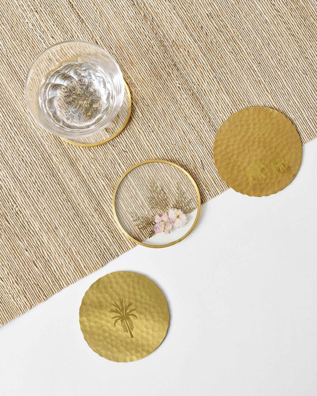 Palm Grove coasters on a woven mat with a glass of water on one.