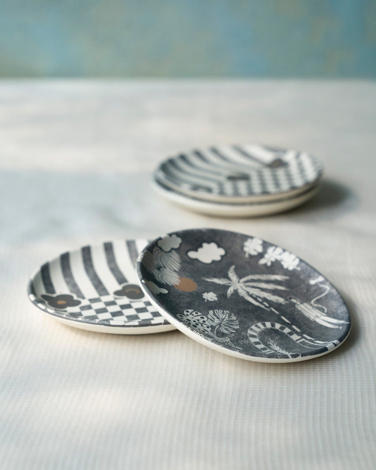 Mandovi tea plates showing palm scene and stripe-checker patterns.