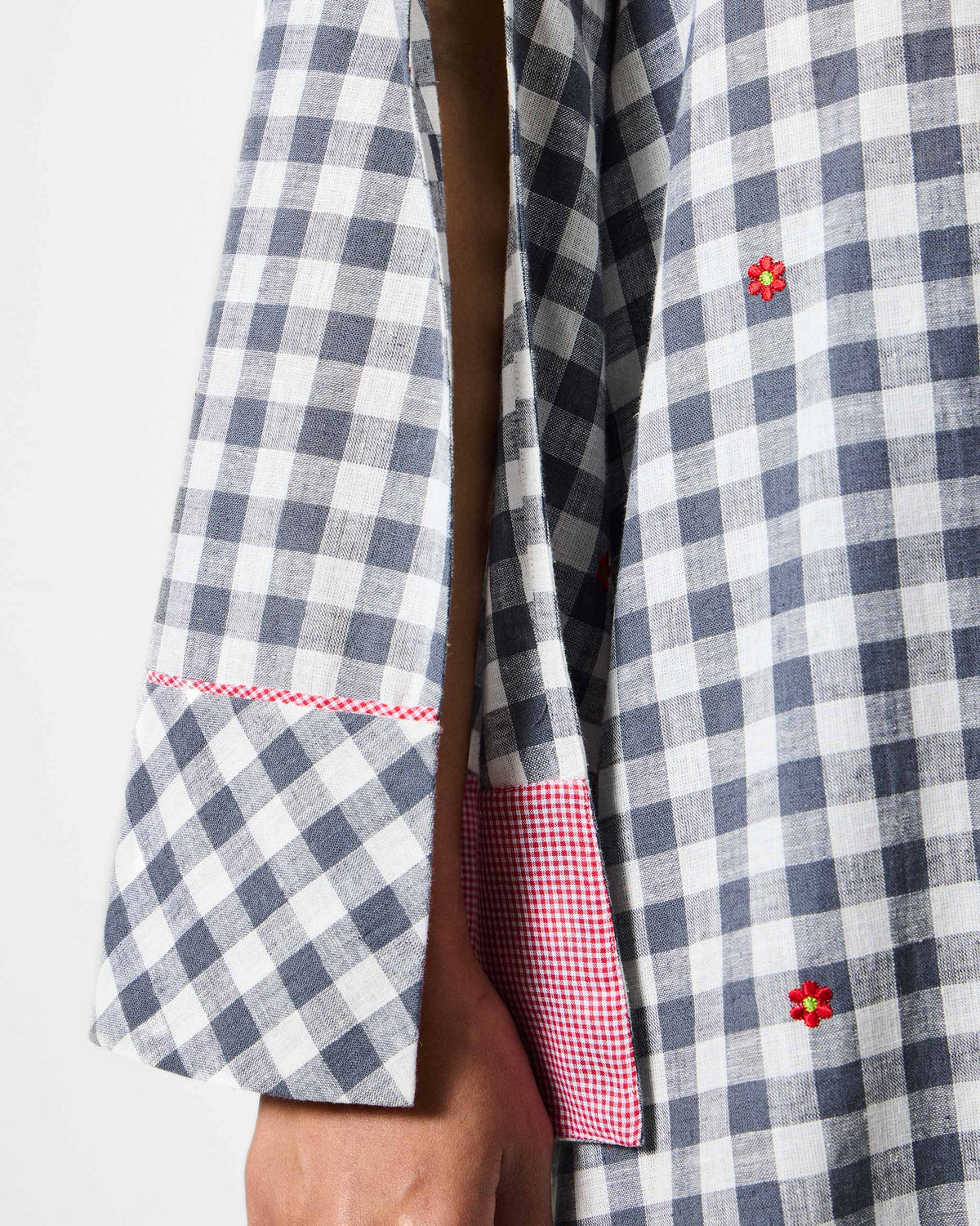 Close-up of a slit sleeve with red embroidery on a grey and white check kurta.