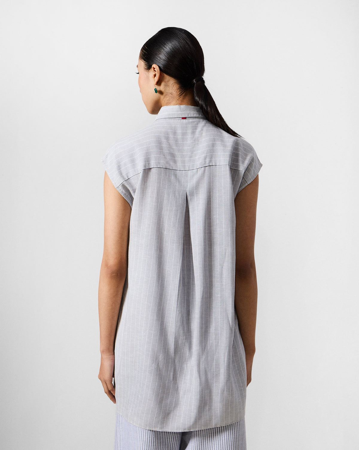 Back of a grey and white striped Rin top with a center box pleat.