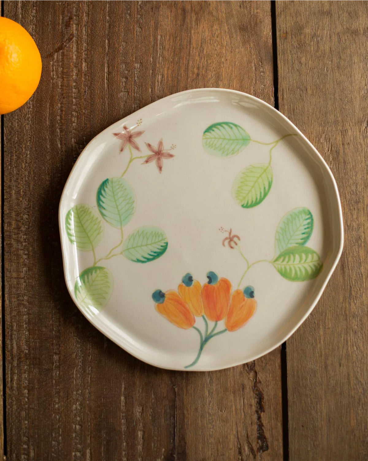 Mandovi side plate with cashew fruits, green leaves and pink stars.