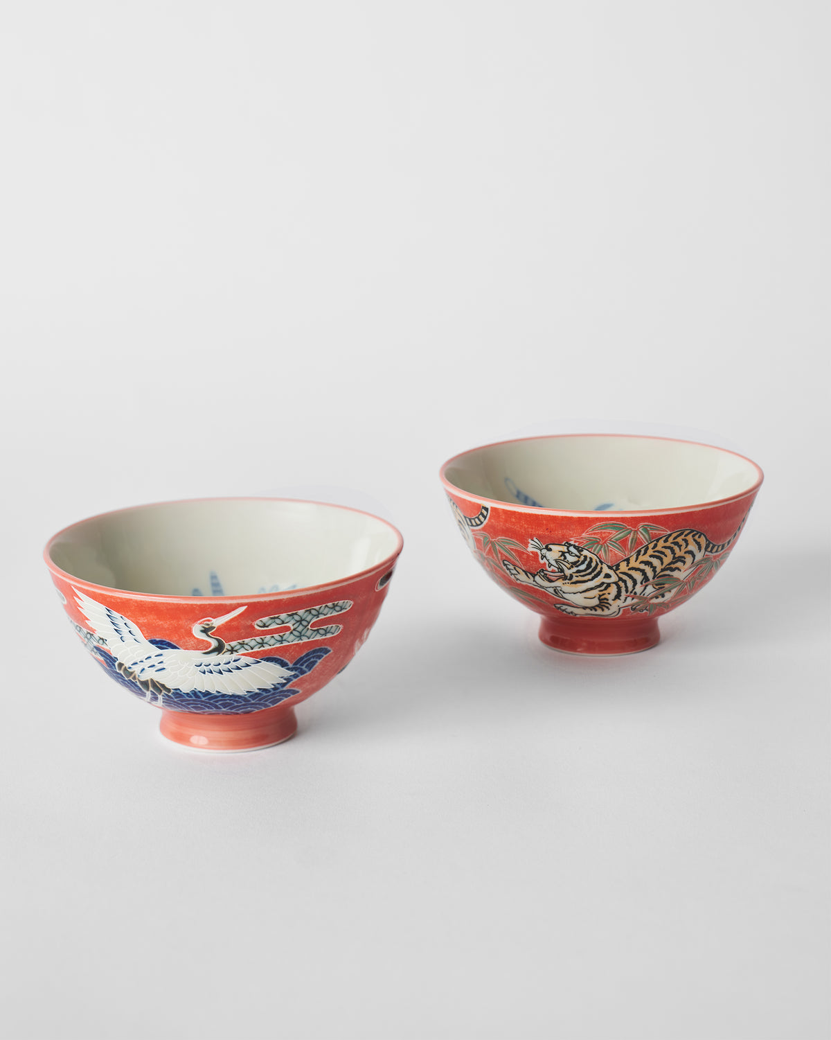 Pair of red Crane and Tiger bowls showing a crane and a tiger motif.