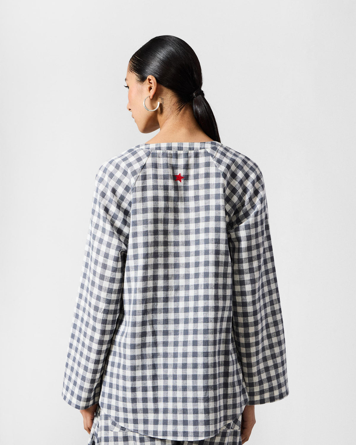 Back of a charcoal and white check Zil top with a red star embroidery.