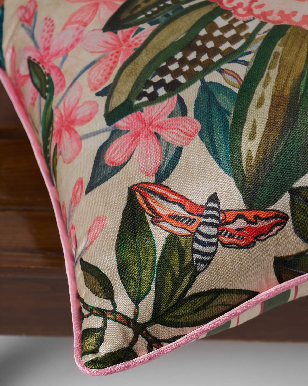 Close-up of Buransh Cushion Cover showing a red moth among pink flowers and leaves.