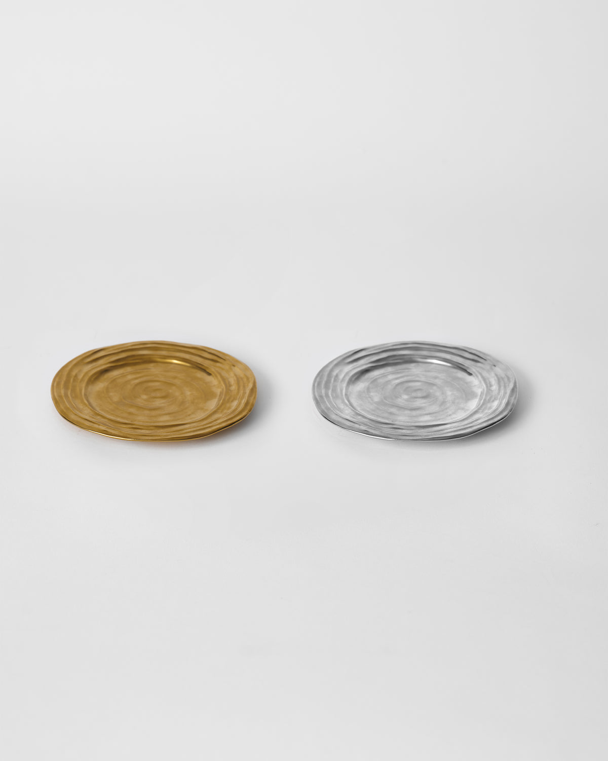 Dhaara Quarter Plates in gold and silver side by side on a white surface.