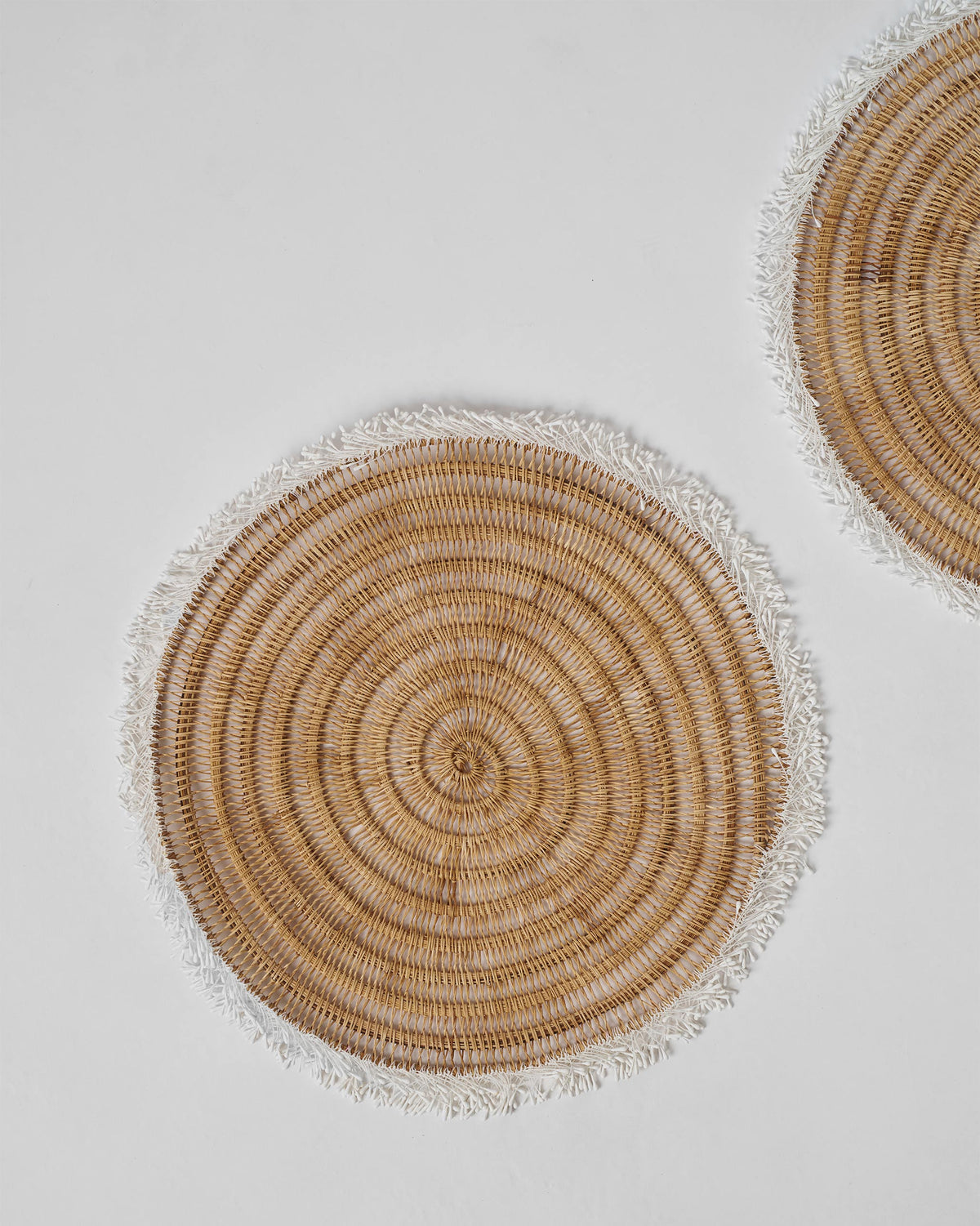 Close-up of a Kaveri Placemat showing its round woven pattern and fringed edge.