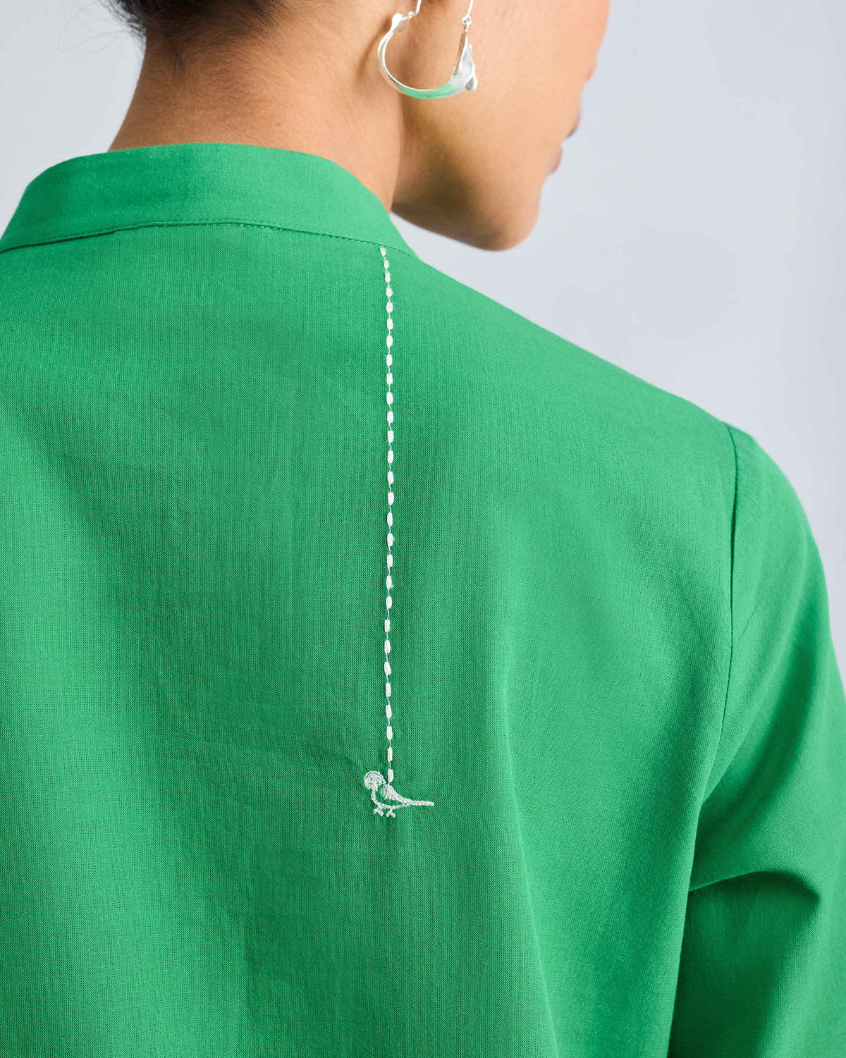 Close-up of white bird embroidery on the back of a green kurta.