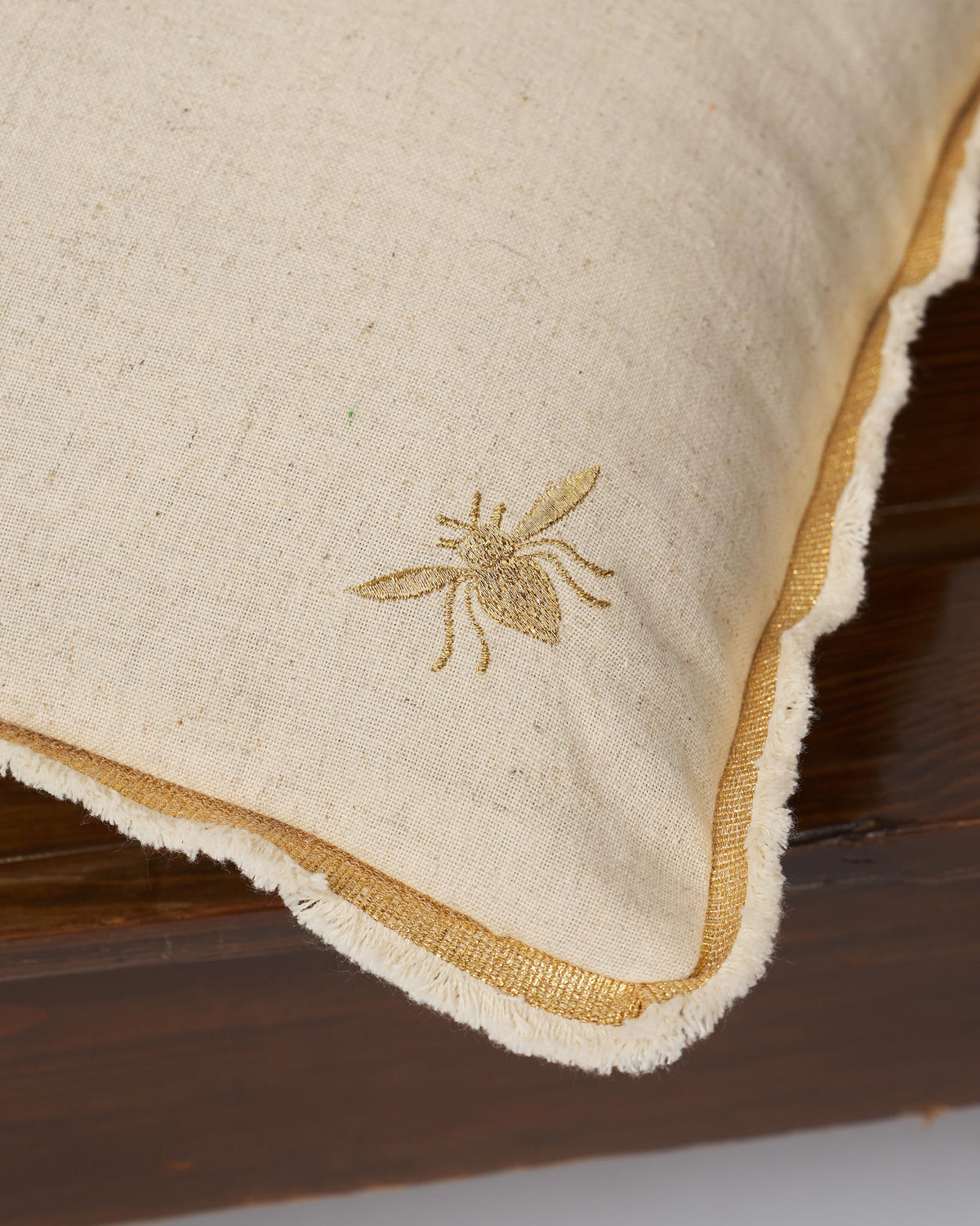 Close-up of the Madhu cushion cover showing a gold embroidered bee.