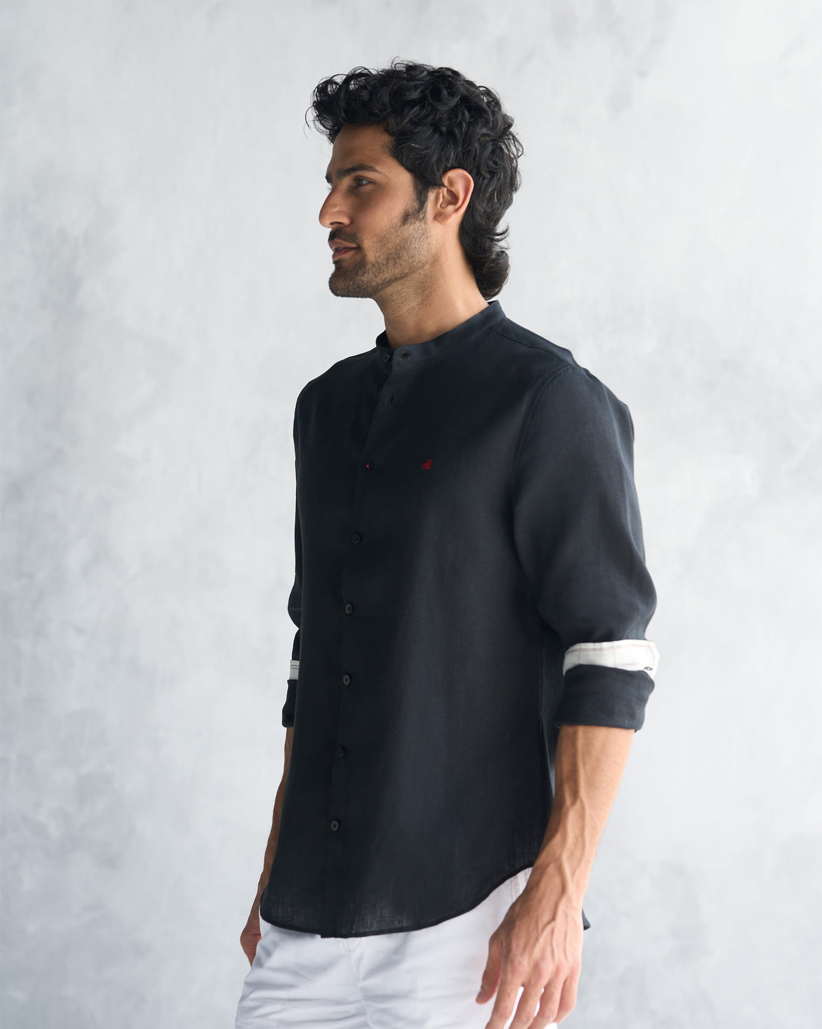Side view of a black Nawab Shirt with rolled sleeves and striped cuff lining.