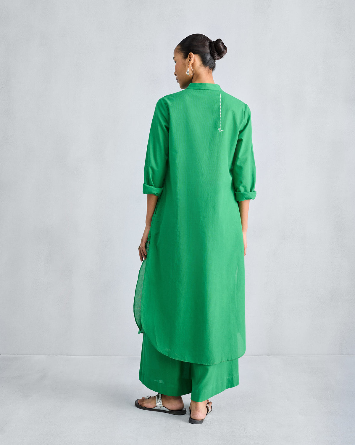Back of a green long kurta worn with matching wide-leg trousers.