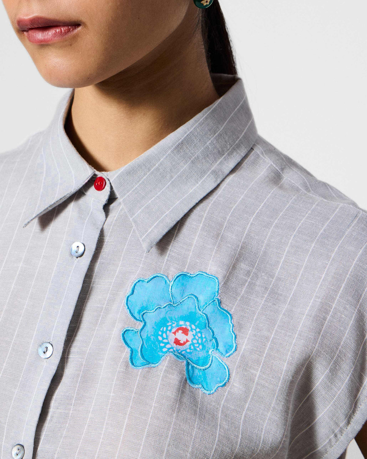 Close-up of blue floral embroidery on a grey and white striped Rin top.